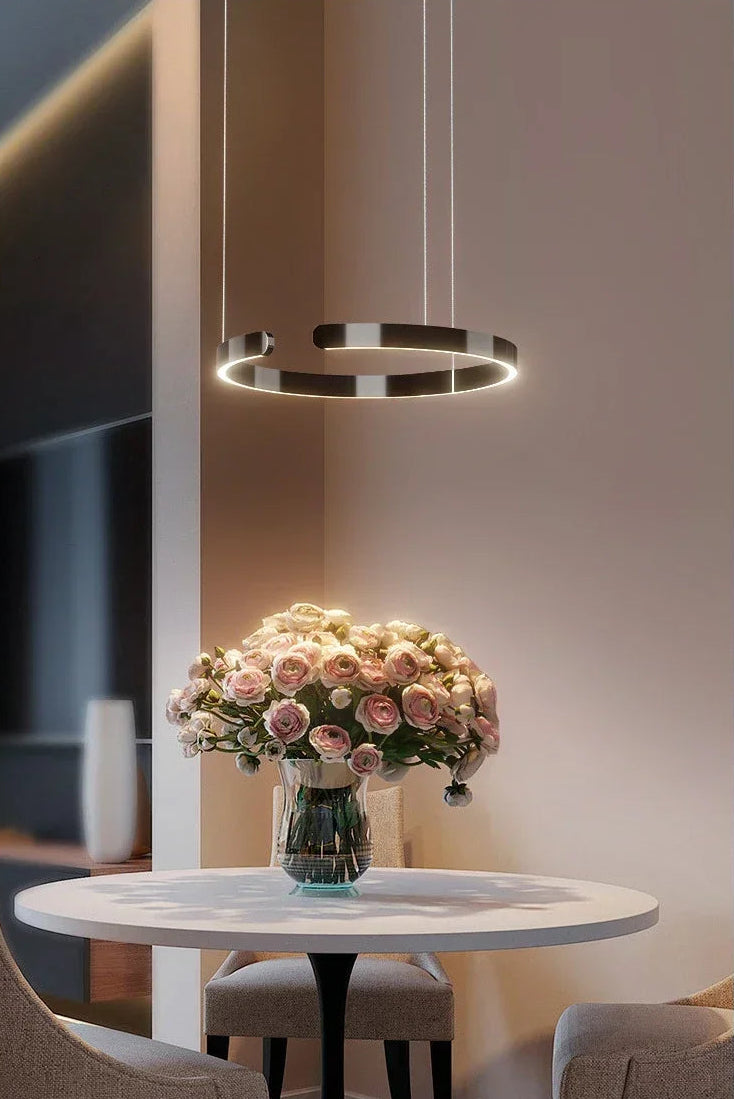 Modern interior design with a round table, vase of flowers, and hanging light fixture.