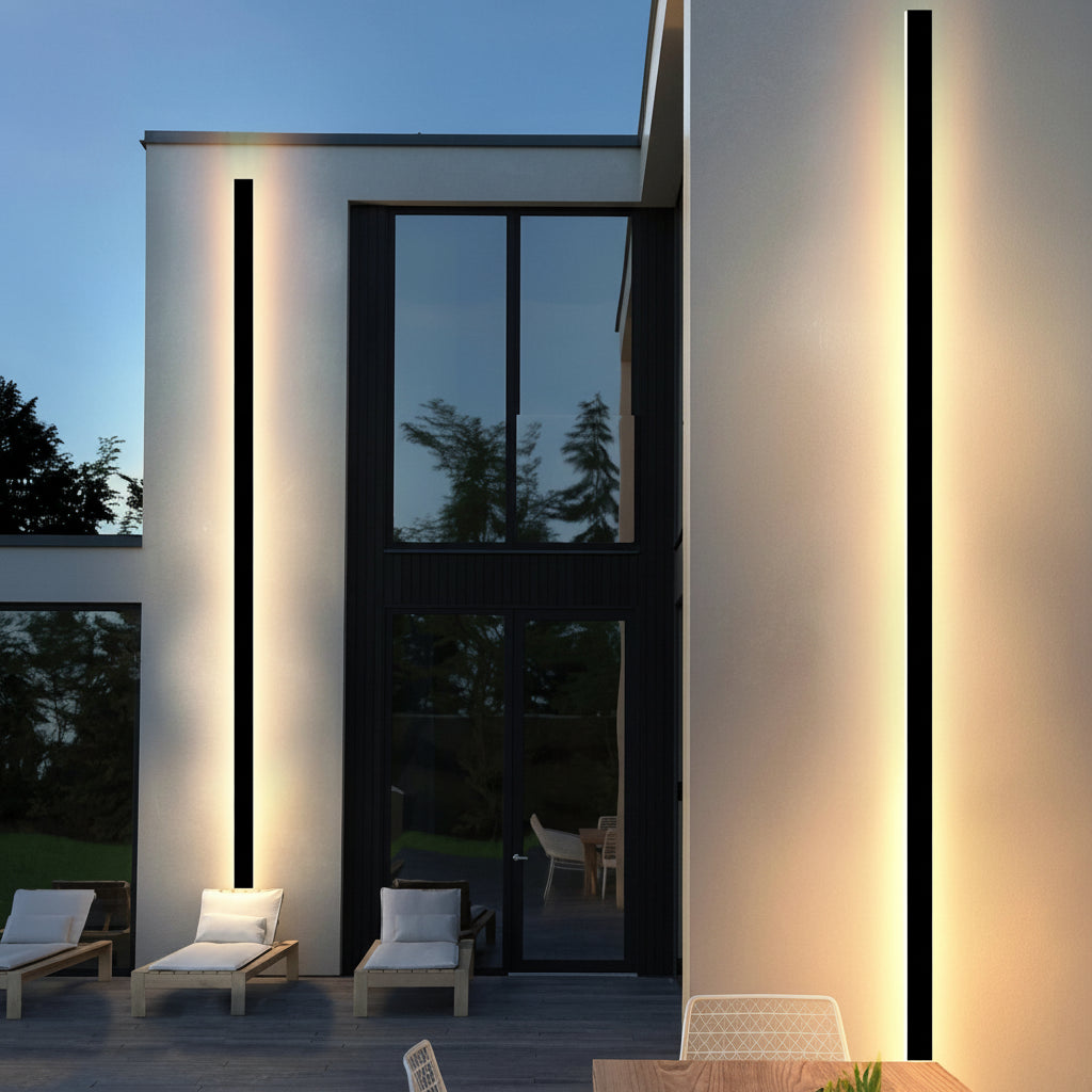 Modern house exterior with illuminated windows and outdoor seating area.