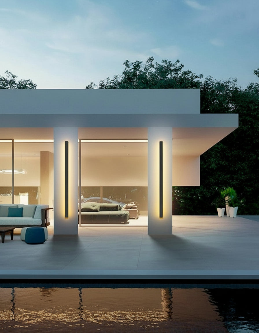 Modern outdoor patio with a sleek wall lamp, surrounded by greenery and a pool.