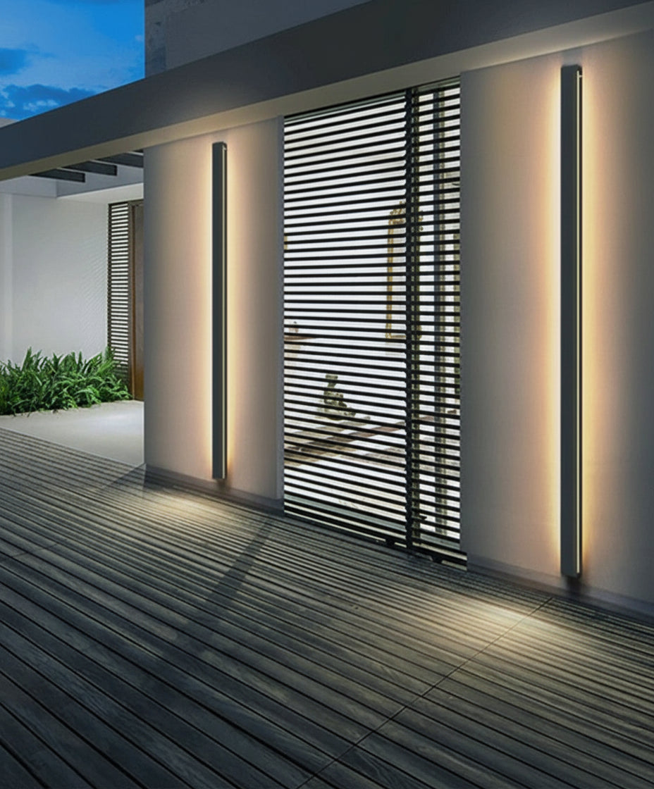 Modern outdoor wall lights on a building exterior with a wooden deck and plants.
