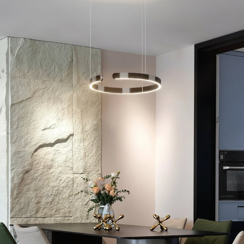 Modern interior with pendant light, stone wall, and decorative items on a table.