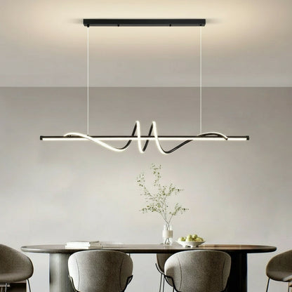 Modern pendant light hanging above a dining table with chairs in a minimalistic room.