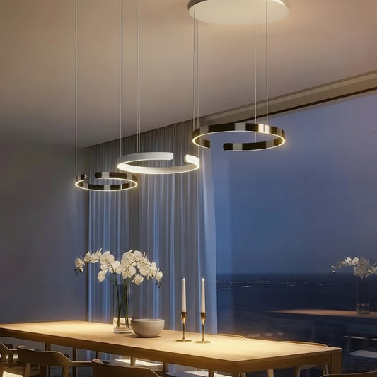 Modern pendant lights hanging above a dining table with a scenic view in the background.